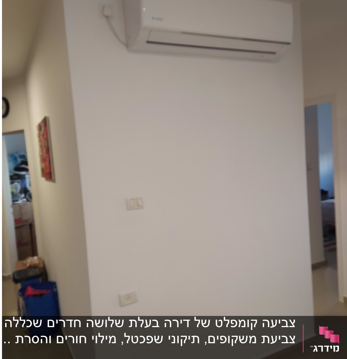 קיר לבן עם מזגן תלוי ותמונה קטנה
